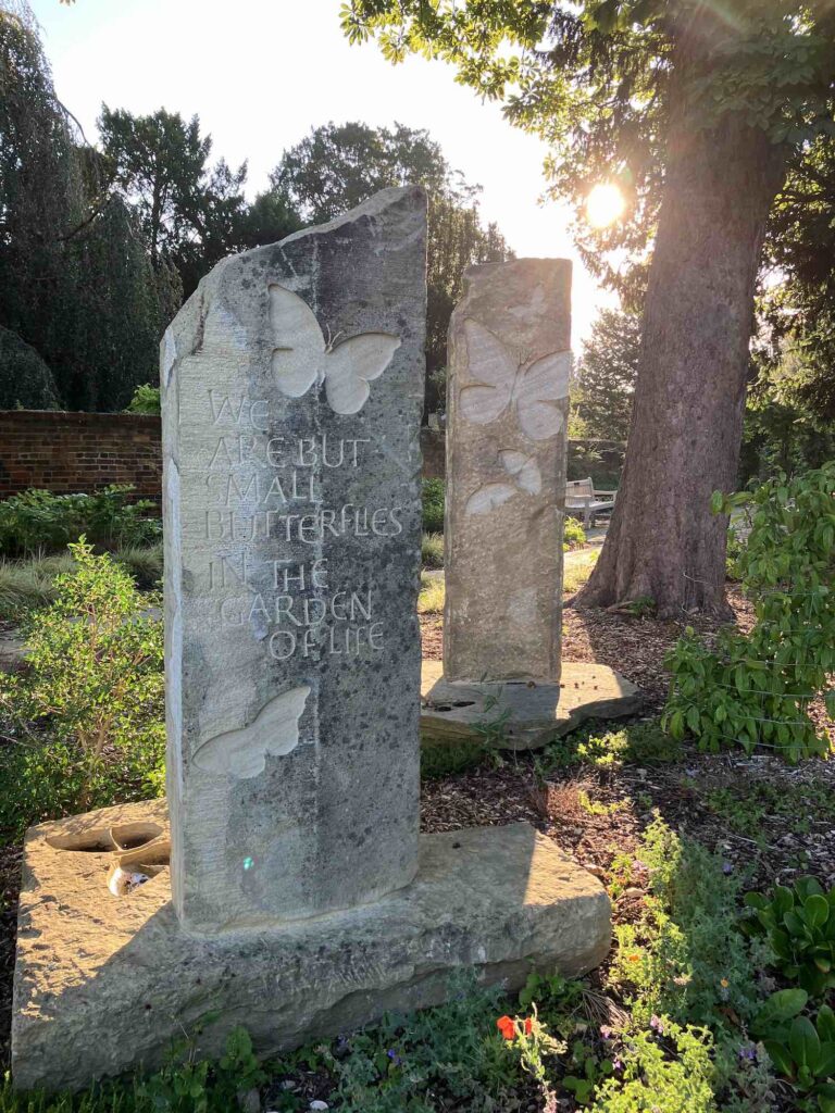 Stone memorial markers with a large and small butterfly engraved on. Message 'we are but small butterflies in the garden of life'.